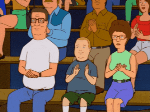 a group of people are sitting in a stadium clapping