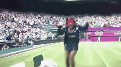 a woman is dancing on a tennis court in front of a large crowd .