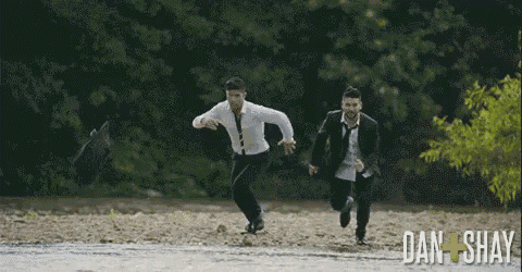 two men in suits and ties are running through a body of water with the words dan shay below them