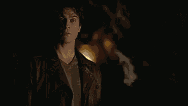 a man is standing in a dark room with a light shining on him .
