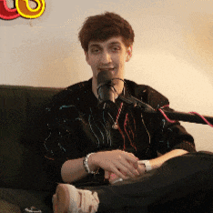 a man is sitting on a couch with a microphone in front of him