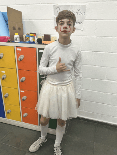 a boy dressed as a clown giving a thumbs up in front of a sign that says pino