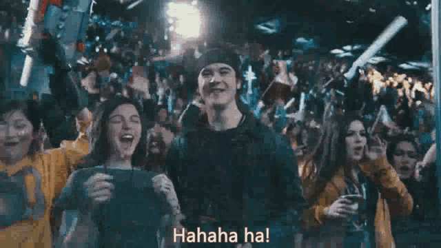 a man and a woman are standing in front of a crowd of people laughing and holding confetti .