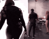 a woman in a black sweater is walking in a room with a man in a black shirt .
