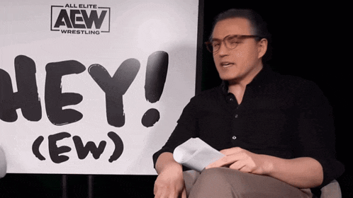 a man is sitting in front of a sign that says hey