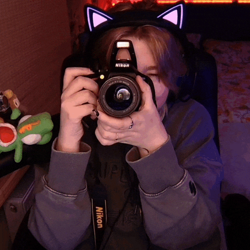 a person wearing a cat ear headset holds a nikon camera
