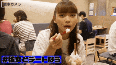 a woman in a white shirt is eating ice cream with a red spoon in a restaurant