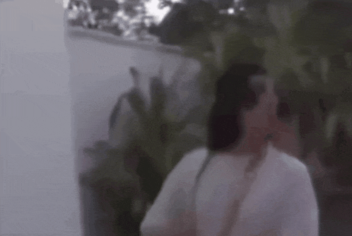 a blurry picture of a woman in a white dress standing in front of a wall .