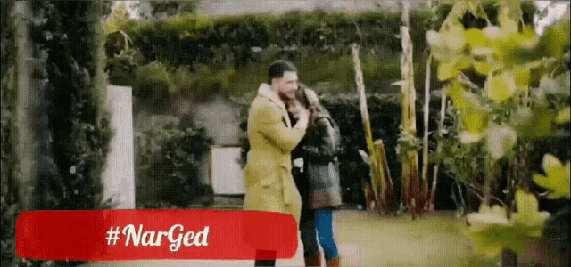 a man in a yellow coat is hugging a woman in a black coat
