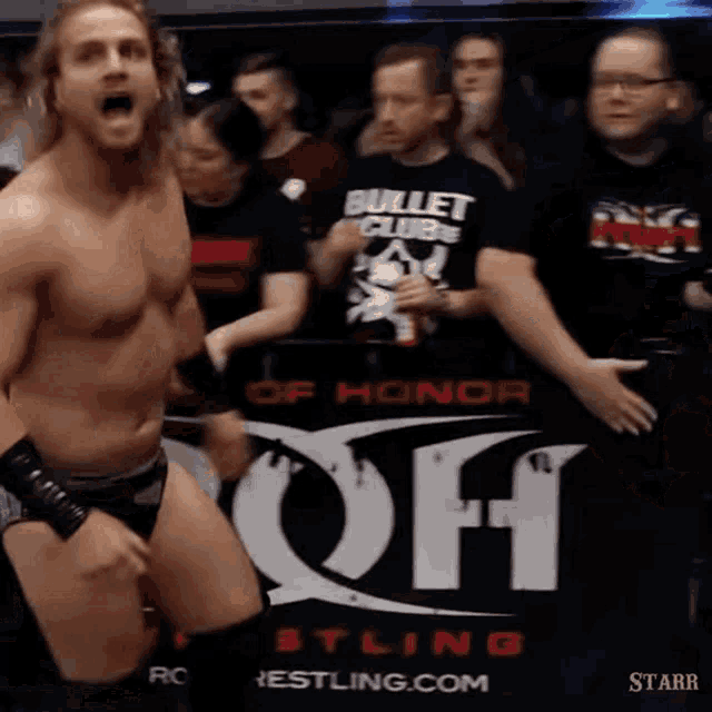 a wrestler stands in front of a sign that says bullet club wrestling