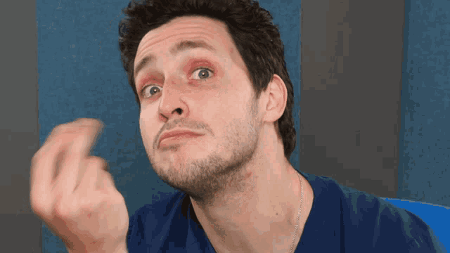 a man in a blue shirt is making a funny face with his hand