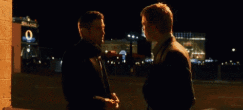 two men are standing next to each other in front of a building with the number 0 on it