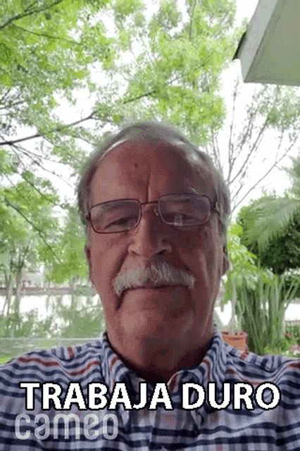 an older man with glasses and a mustache is wearing a shirt that says trabaja duro cameo