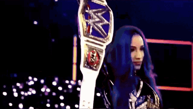 a woman with blue hair is holding a championship belt .
