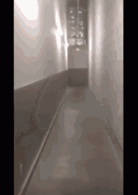 an empty hallway with a red exit sign on the wall