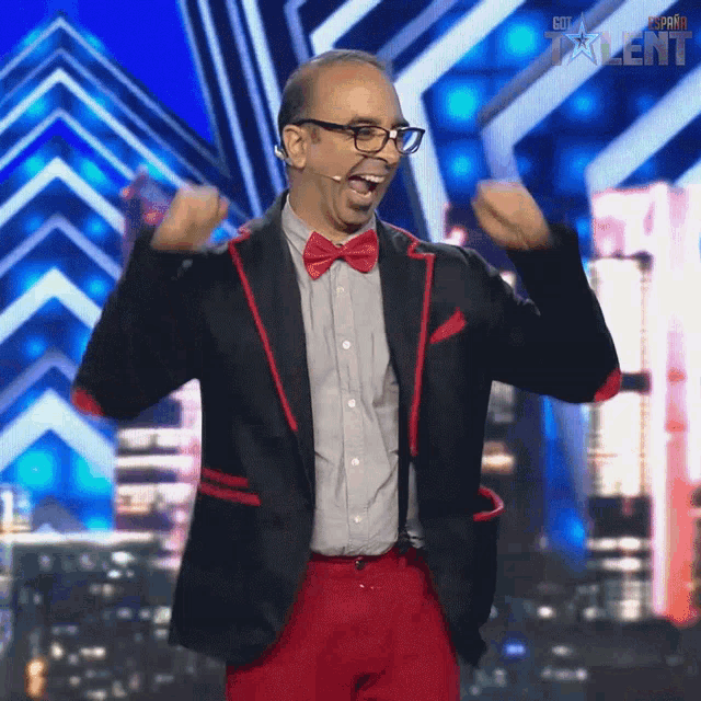 a man in a black jacket and red pants stands on a stage with the word talent on the bottom