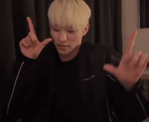 a young man with blonde hair is making a funny face with his hands .