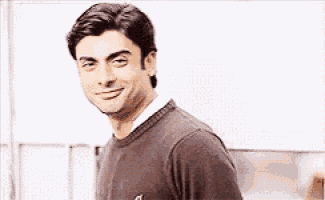 a man wearing a brown sweater is smiling and looking at the camera .