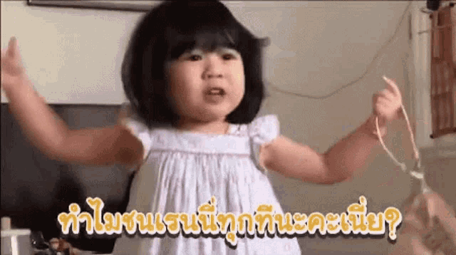 a little girl in a white dress is holding a string in her hands .