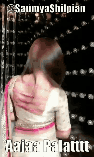 a woman in a white and pink dress is standing in front of a wall with bubbles .