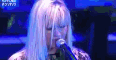 a woman singing into a microphone with the words show ao vivo on the bottom right