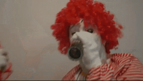 two clowns sitting at a table with a glass of water in front of them