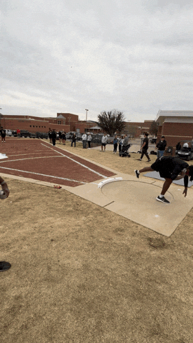 a man is throwing a ball on a track in front of a large building