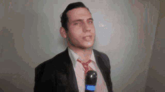 a man in a suit and tie is holding a microphone with the letter c on it