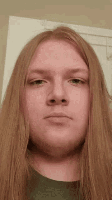 a man with long blonde hair and a beard is looking at the camera