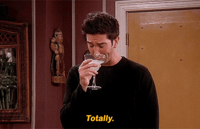 a man drinking from a martini glass with the word totally in yellow letters