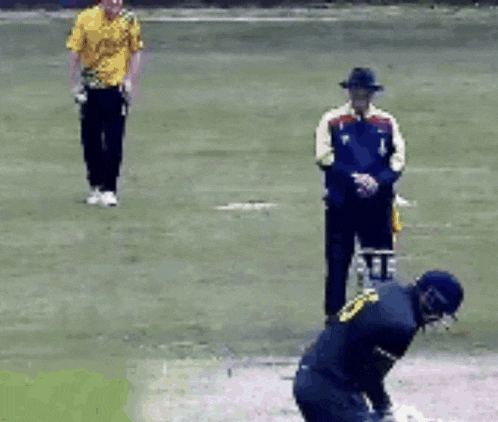 a man in a yellow shirt is running on a cricket field while another man watches .