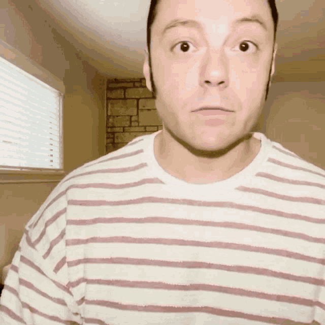 a man is wearing a striped shirt and making a surprised face