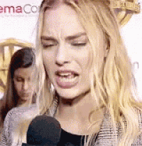 a woman is talking into a microphone and making a face .