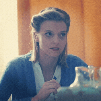 a woman wearing a blue sweater and white shirt is sitting at a table
