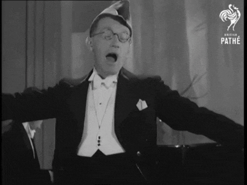 a man in a tuxedo is singing in a black and white photo that says pathe on the bottom