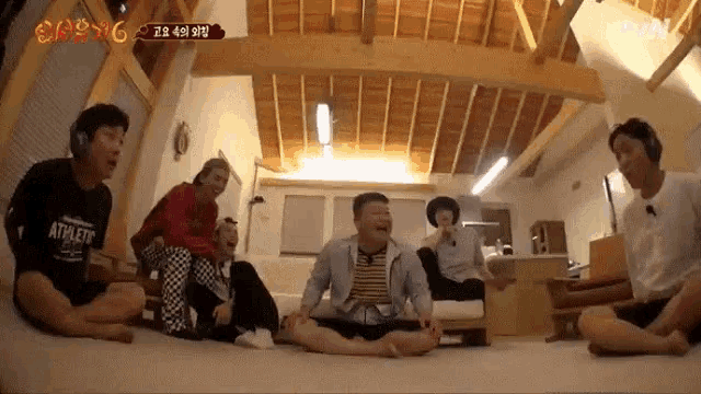 a group of people are sitting on the floor in a living room wearing headphones and a shirt that says athletic on it .