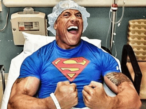 a man in a hospital bed wearing a blue superman shirt
