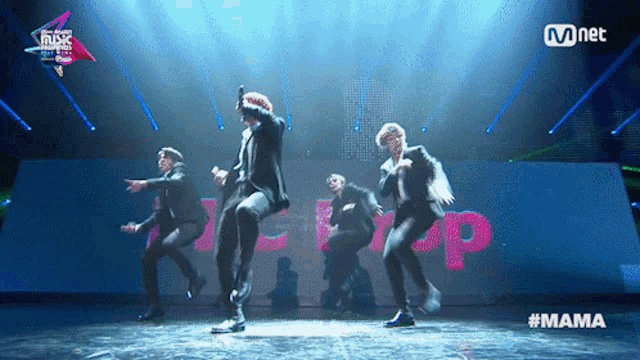 a group of men are dancing on a stage in front of a sign that says mnet