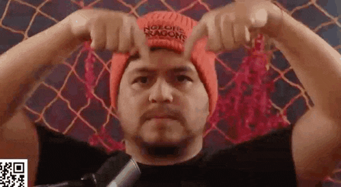 a man wearing a red beanie and a black shirt is making a funny face .