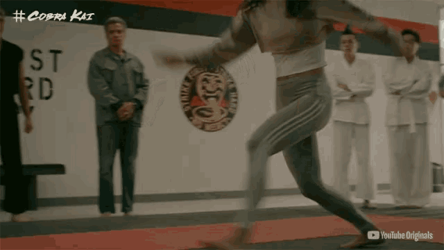 a woman is jumping in front of a wall that says cobra kai