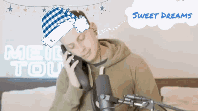 a man wearing a santa hat is talking on a cell phone in front of a sweet dream sign