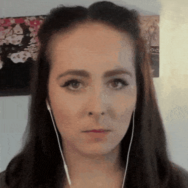 a woman wearing ear buds looks at the camera