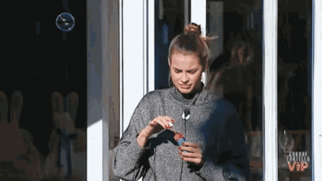 a woman is standing in front of a window holding a soap bubble .