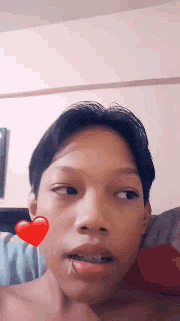 a young boy with braces on his teeth has a red heart on his face