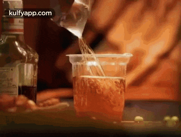 a close up of a person pouring a drink into a cup .