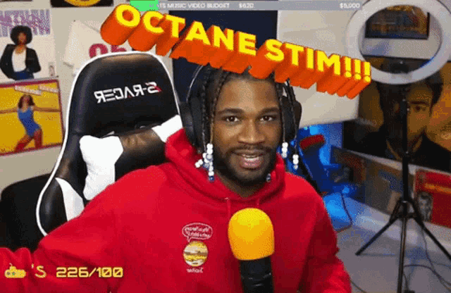 a man in a red hoodie is sitting in front of a microphone with the words octane stim on the screen behind him