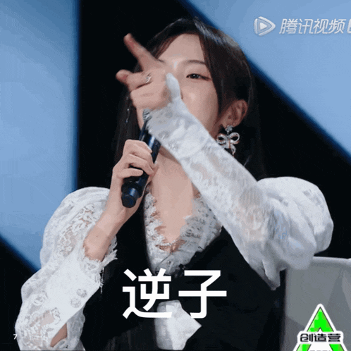a woman holding a microphone with chinese writing on the bottom right