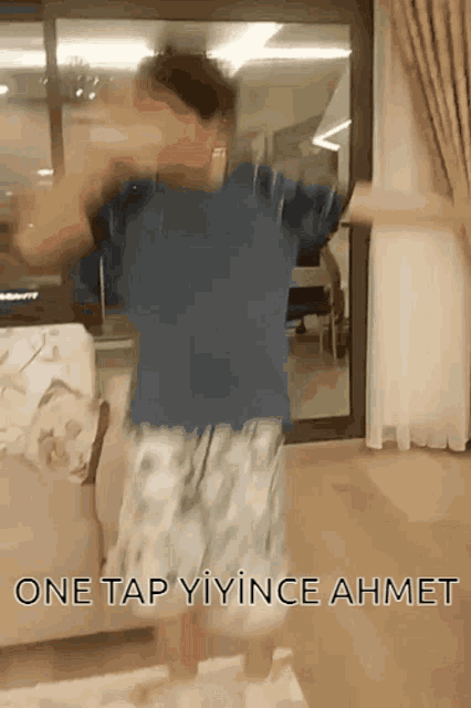 a man is dancing in a living room with the words one tap yiyince ahmet written on the bottom