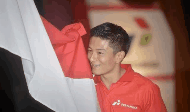 a man in a red shirt is holding a red , white and blue flag .