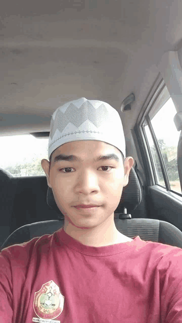 a man wearing a red shirt and a white hat is taking a selfie